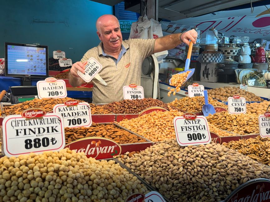 Um vendedor exibindo uma variedade de nozes em um movimentado mercado turco.